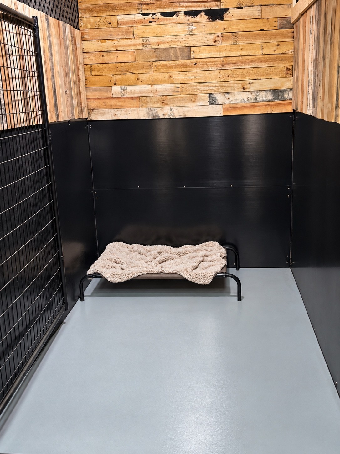 Boarding suite with wood walls, black panels, and a raised bed with a soft blanket